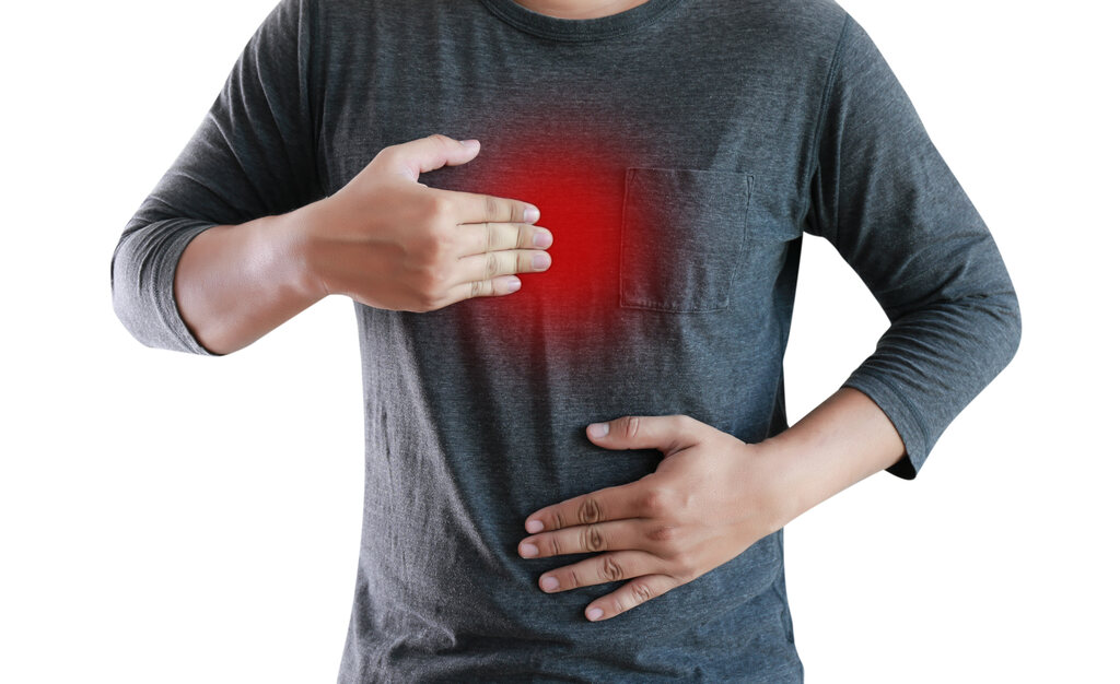 Homem com a mão no peito e dor típica de refluxo