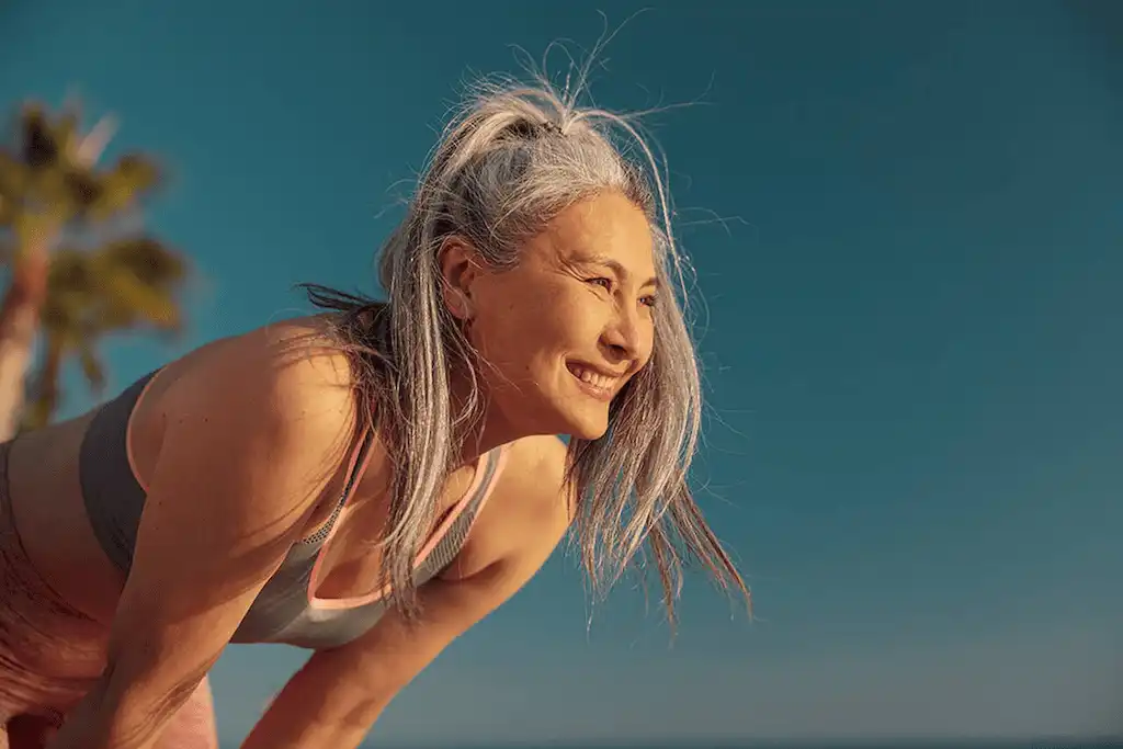 Mulher de meia-idade sorrindo e se exercitando, simbolizando a fase da menopausa e as mudanças nos hormônios femininos.