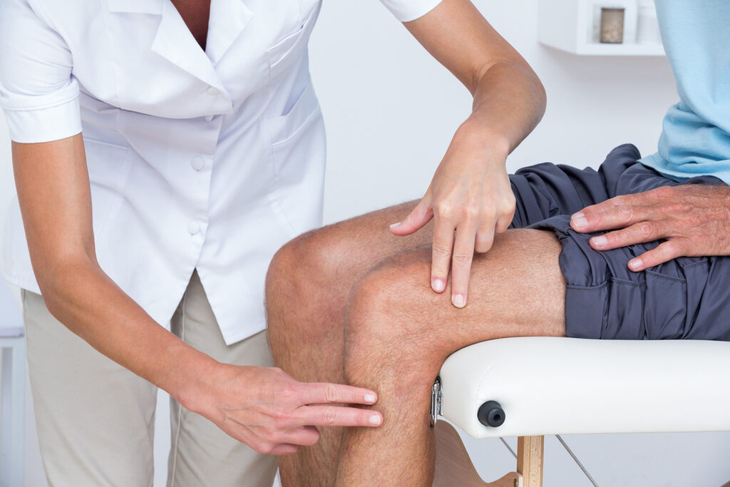 Profissional de saúde examinando joelho de paciente com dor articular